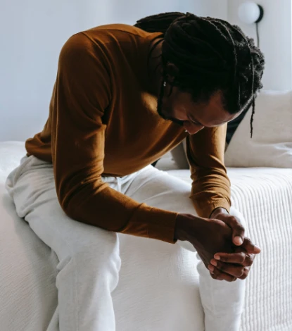 Desperate black man sitting on bed in deep thoughts