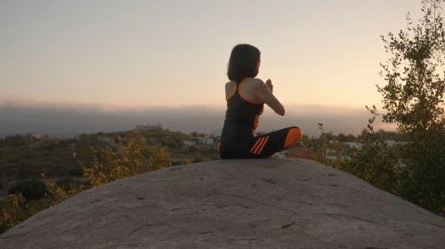A Woman Meditating on Top of a Rock - photo by Los Muertos Crew