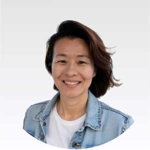Smiling Asian woman wearing a denim jacket and white shirt.