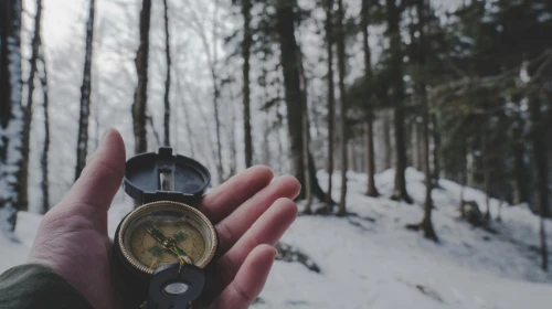 hand holding compass in snowy forest