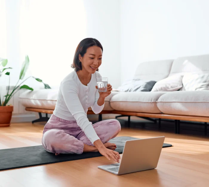 smiling woman looking at laptop screen sitting on floor