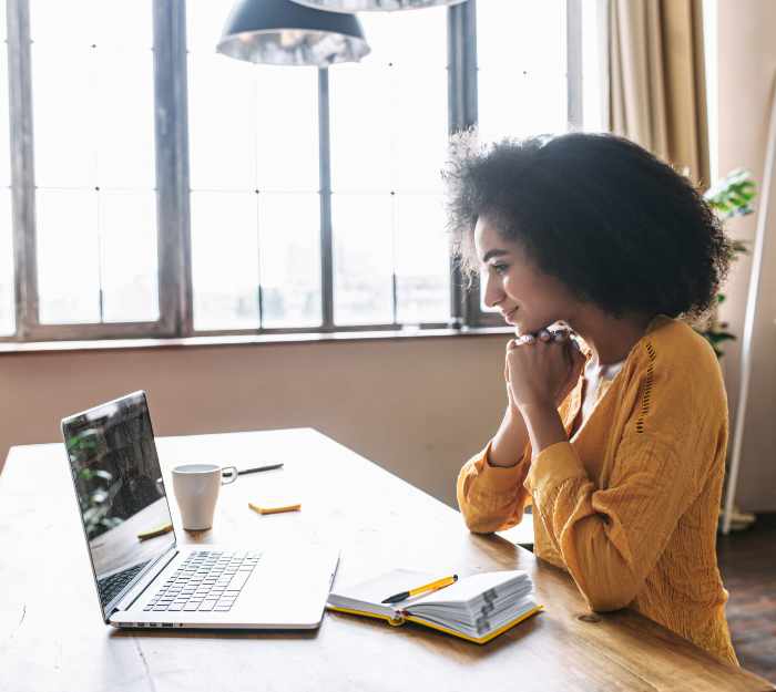 smiling woman looking at laptop screen on desk