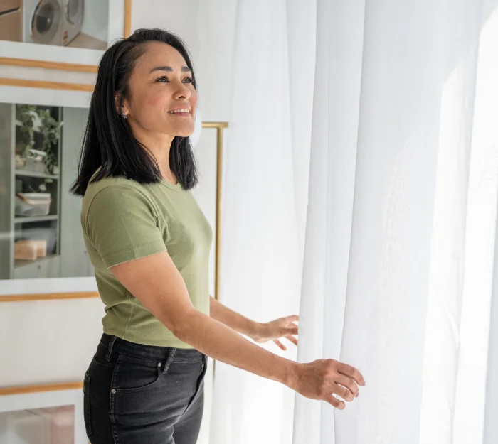 smiling woman arranging curtains